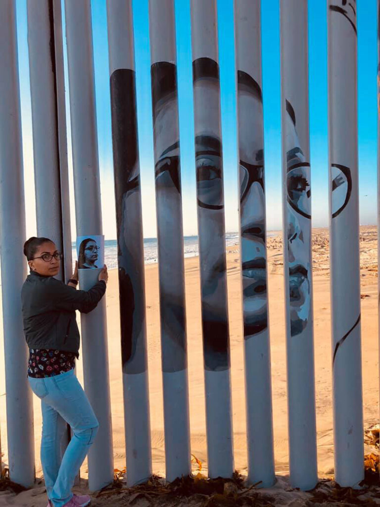Tania Mendoza, a deported childhood arrival from Los Angeles, holds the photo of herself next to her image on the border wall.