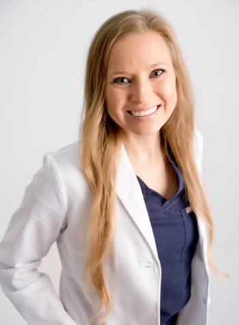 Portrait of Dr. Ryann Christensen in white medical jacket and navy blue scrubs.