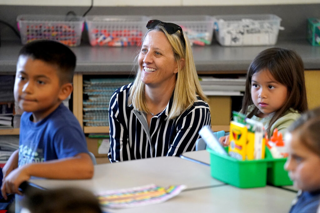 Dr. Corrine Folmer smiles while sitting at a table with two elementary age kids.