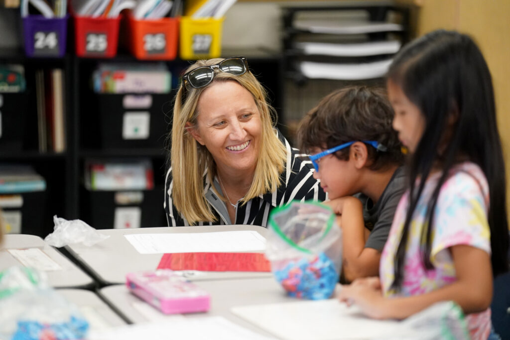Dr. Corrine Folmer smiles at a student sitting at a table.