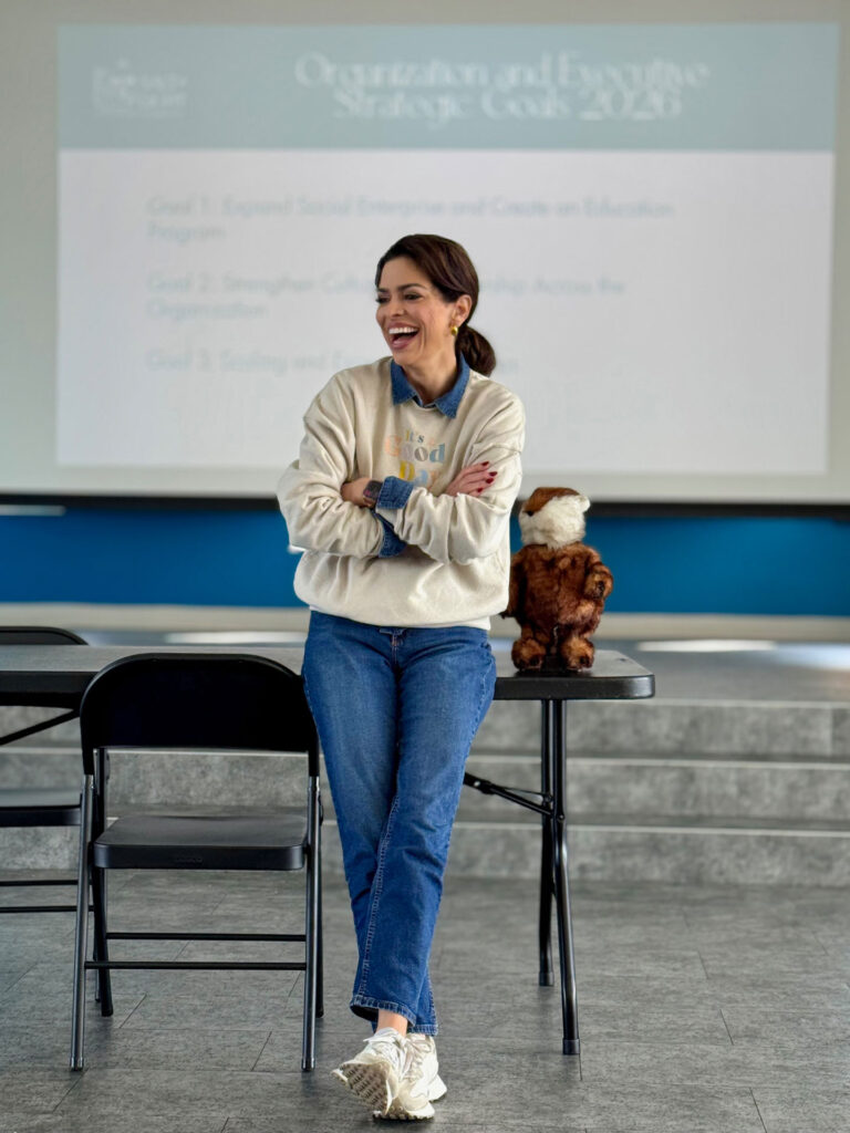 Adrianne Hillman laughs while leaning against a table.