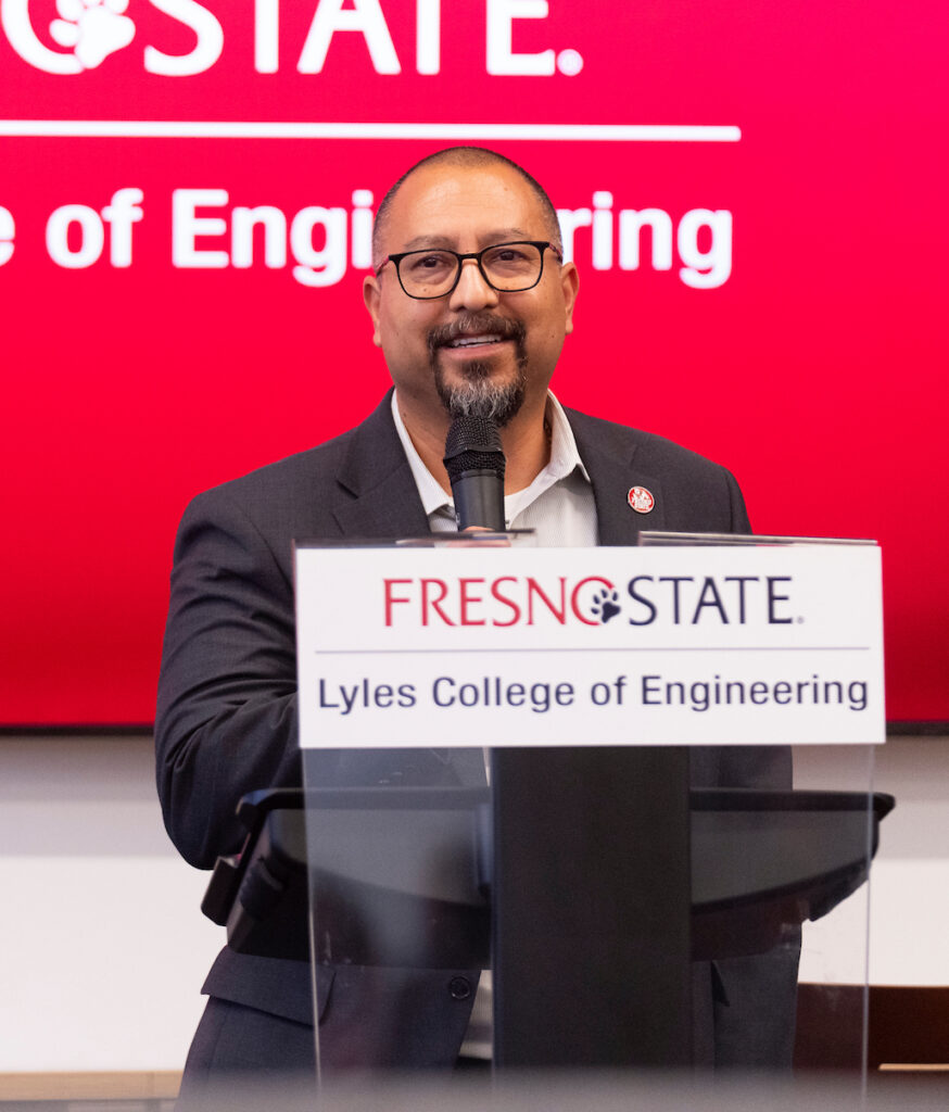 Hernan Maldonado stands at a podium in front of a red screen that reads Fresno State Lyles College of Engineering.