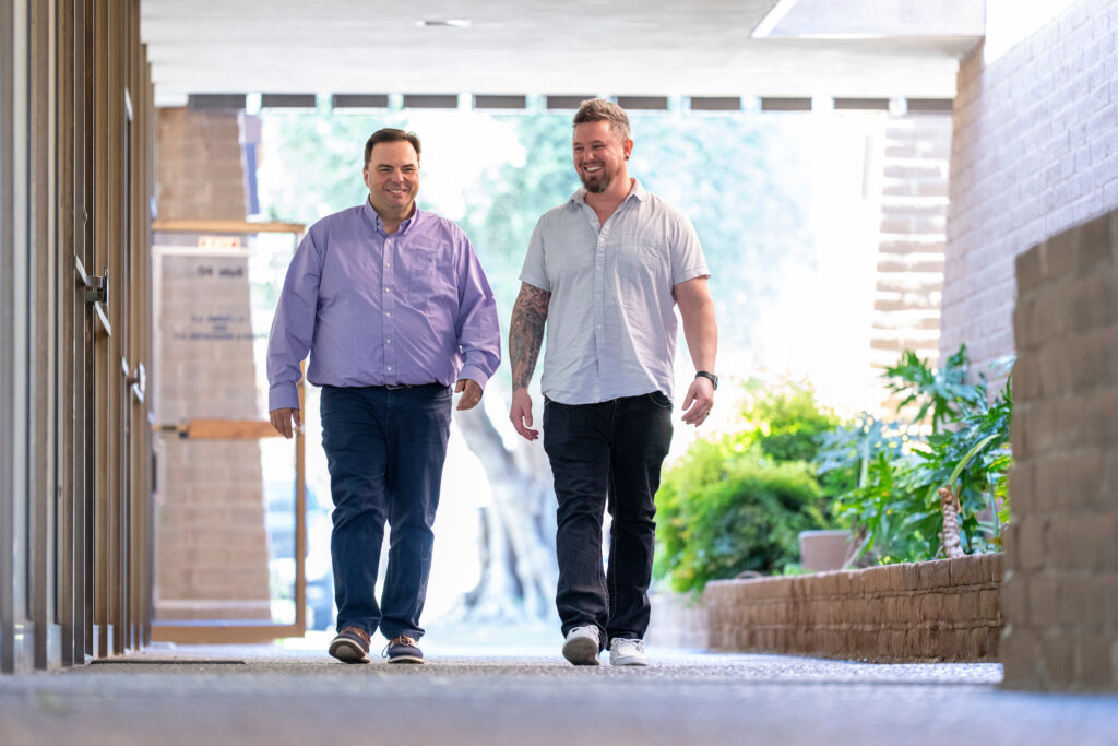 Dr. Kyle N. Weir and Nathan Tomshak walk together outside in the Fresno Family Counseling Center.