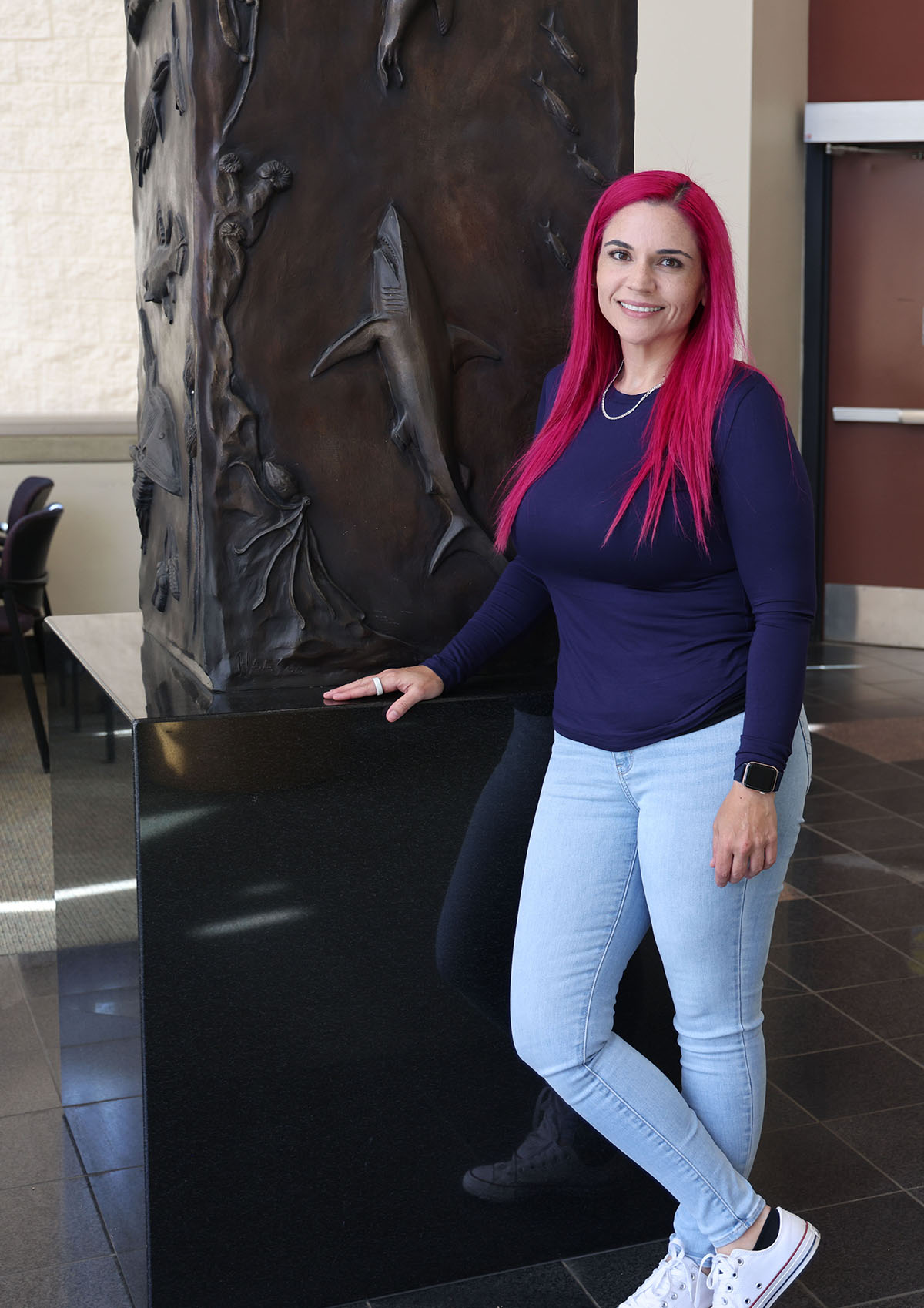 Fresno State biology student Felicia Sandoval stands next to marine life sculpture in the Science II building rotunda