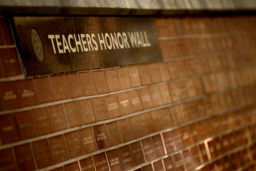 A "Teachers Honor Wall" sign sits over the wall of engraved bricks.