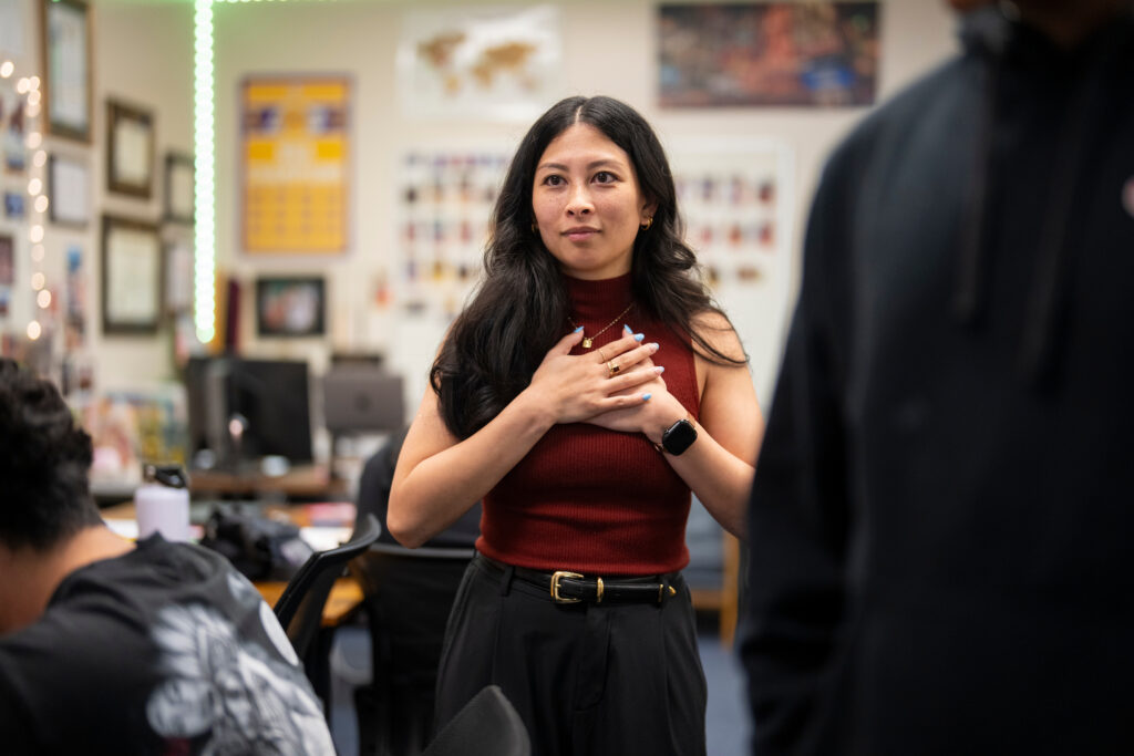 Chrizia Dela Rosa stands in her classroom with her hands over her heart.