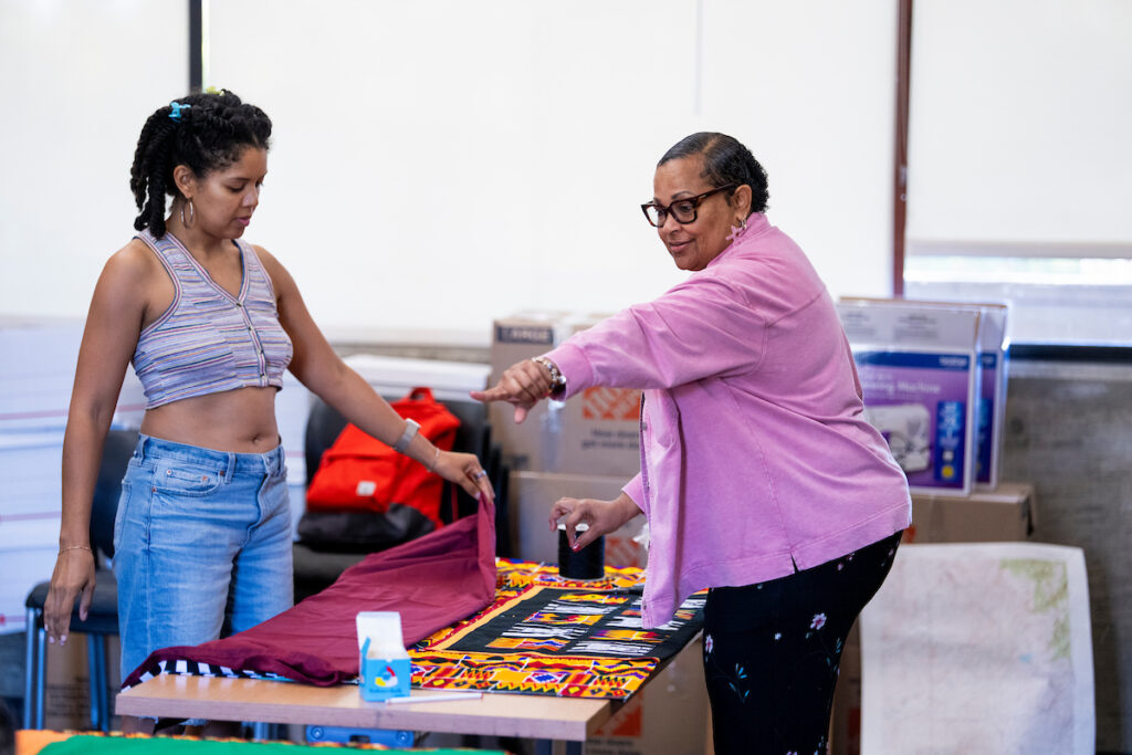 Janel Claybon (left) and a community member work on their shawls.