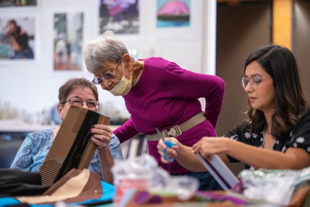 Corky Mills works with a community member and a faculty member on their shawls.
