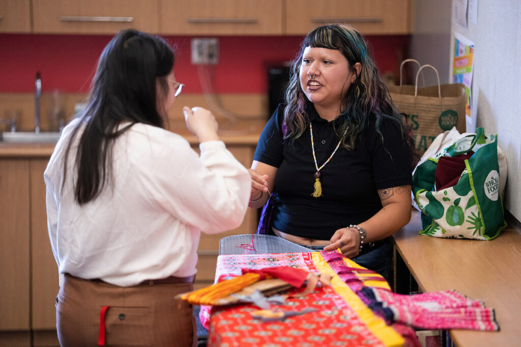 Two women work on a shawl